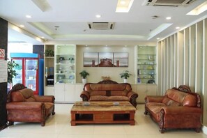 A hotel lobby with leather sofas, a coffee table, and a display of items on shelves. - Jingyi Boutique Hotel (Anqing Petrochemical No.1 Middle School) (Anqing)