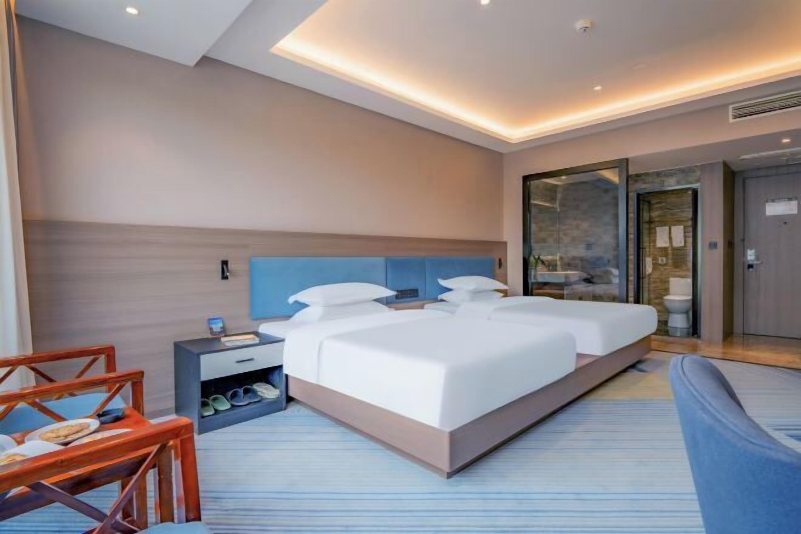 Een moderne hotelkamer met een groot bed, een nachtkastje, een stoel en een douchecabine.