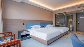 Een moderne hotelkamer met een groot bed, een nachtkastje, een stoel en een douchecabine.