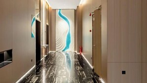 A modern hallway with a reflective marble floor, a wall with a blue wave design, and a door on the right. - Stone Hotel (Kaili Downtown Wanda Plaza) (Kaili)