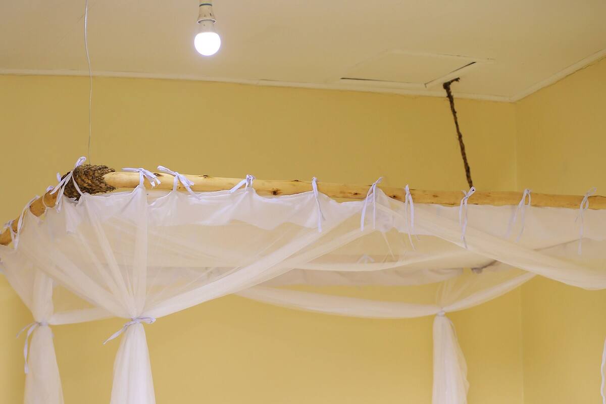 A bed with a wooden frame, a floral bedspread, and a white canopy.