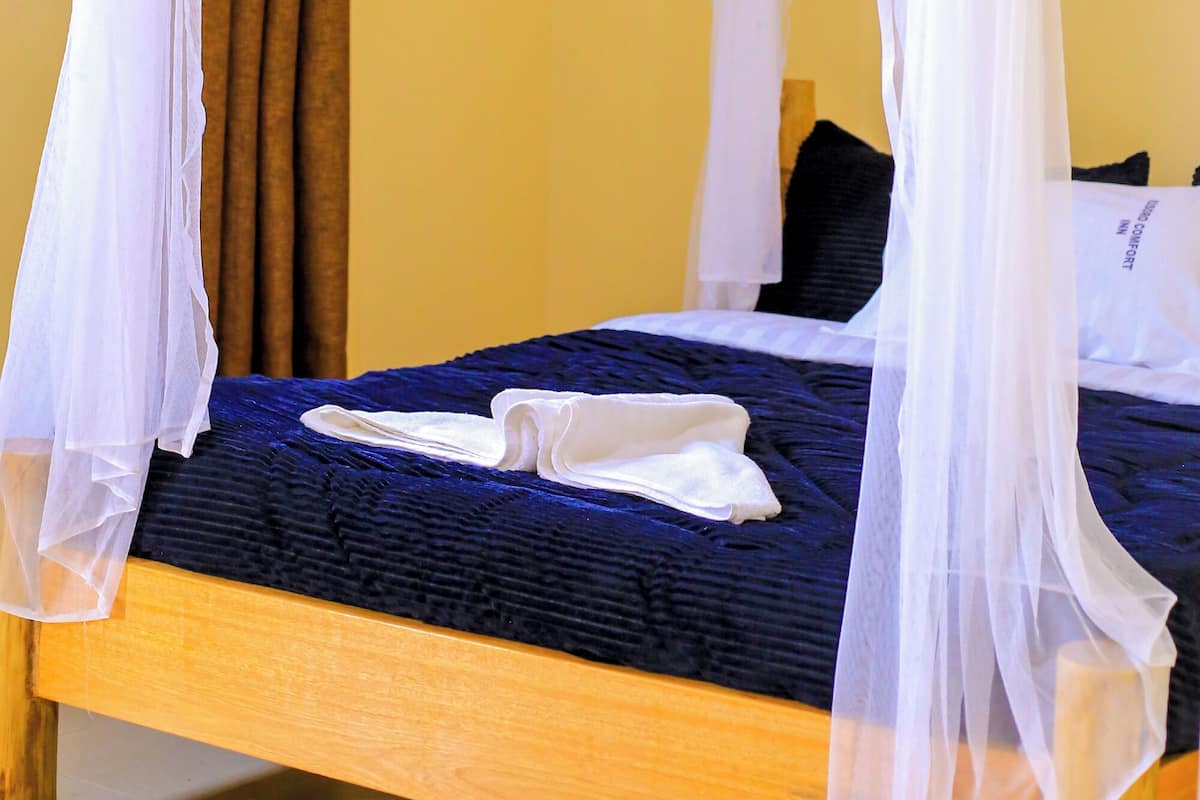 A bed with a canopy, a window with bars, and a curtain.