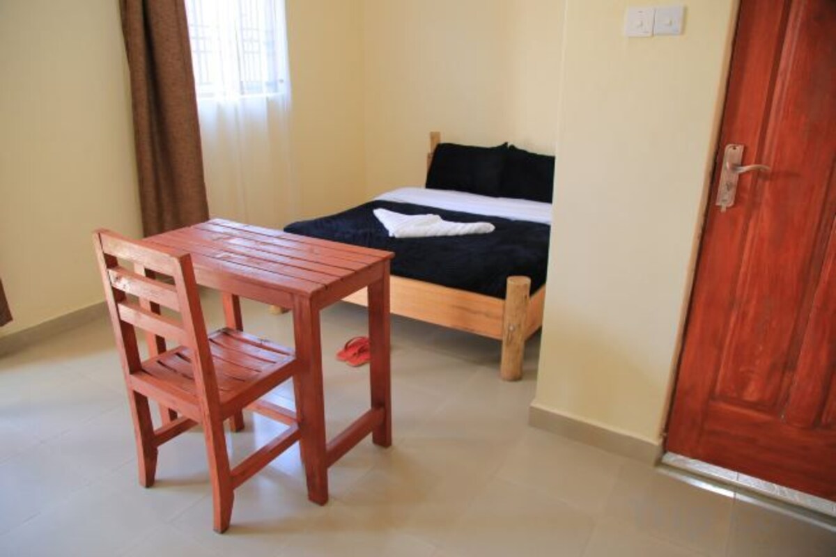 A bedroom with a bed, a wooden table, and a door.