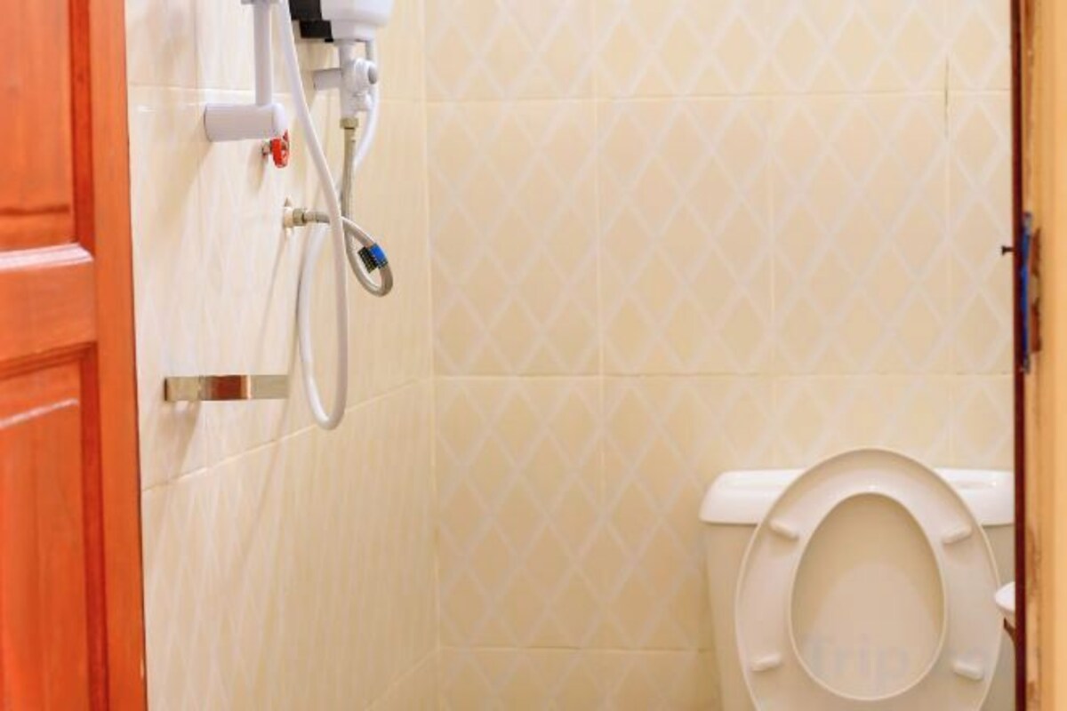 Une salle de bain équipée de toilettes, d’une douche et d’un robinet mural.