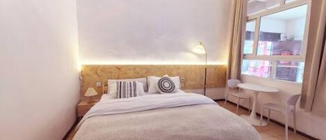 Une chambre à coucher avec un lit, une lampe de chevet et une fenêtre donnant sur un beau paysage.