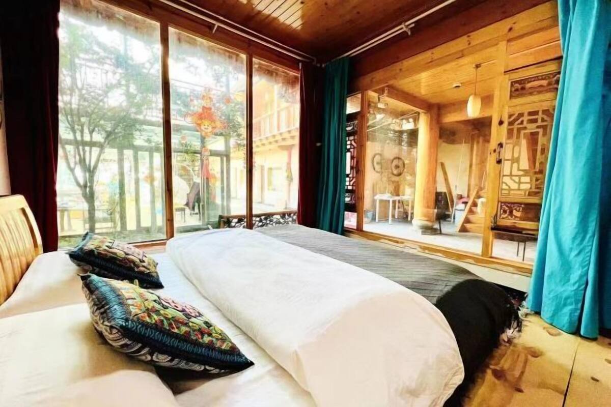 Ein Zimmer in einer Holzhütte mit einem Bett, großen Fenstern und Blick ins Freie.