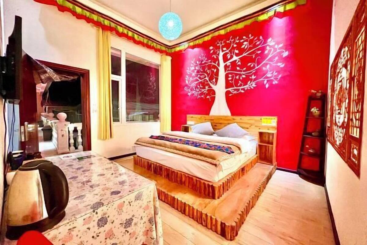 Ein Schlafzimmer mit Bett, Fenster, Wand mit Baum-Mural und roter Wand.