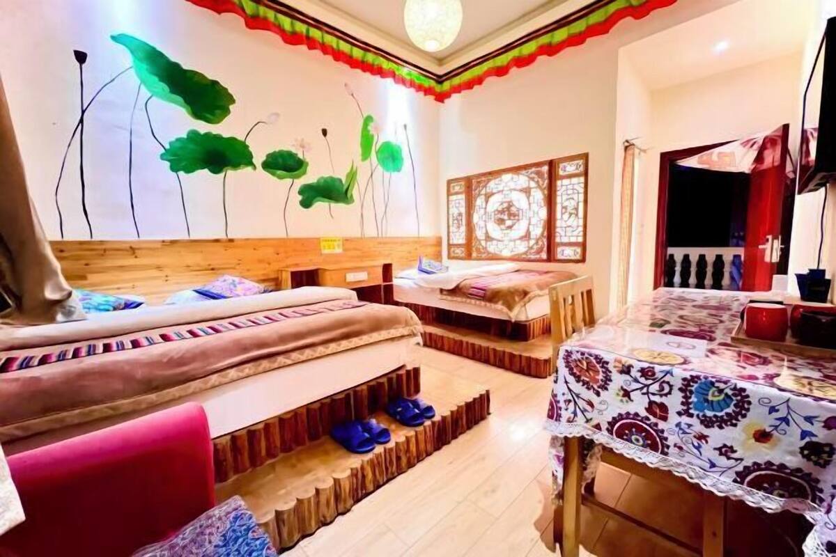 Ein Zimmer mit einem Bett, einem Tisch mit Tischdecke und einer Wand mit dekorativem Muster.