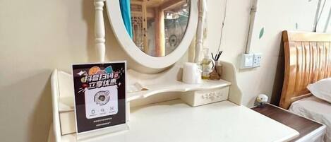 A room with a bed, a bedside table, a mirror, and a wall-mounted shelf with a small decorative item.