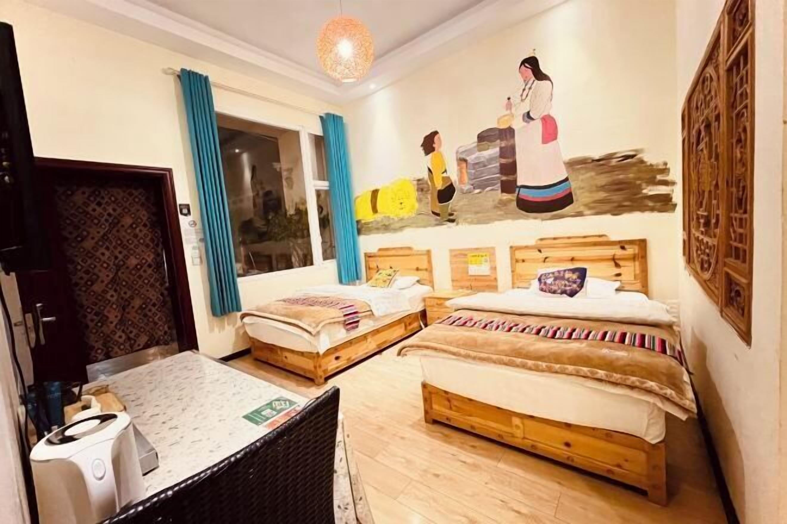 Een kamer met twee houten bedden, een tafel en een muurschildering.