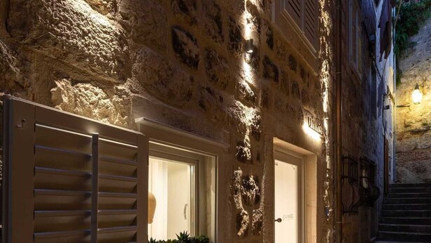 Un edificio de piedra con una banca y una mesa afuera, una puerta con el rótulo 