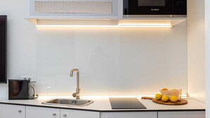 Una kitchenette compacta con microondas, pileta y una pequeña mesada.