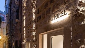 Un edificio de piedra con un letrero que dice "UNIKSE" y una puerta con un panel de vidrio.