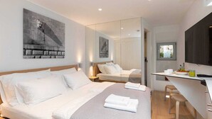 Una habitación de hotel moderna con una cama grande, un escritorio y un espejo.