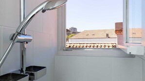 Ein modernes Badezimmer mit Dusche, Fenster und Blick auf die Stadt.