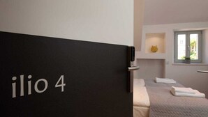 Ein Hotelzimmer mit Bett, Fenster und einer Tür mit der Aufschrift "ilio 4".