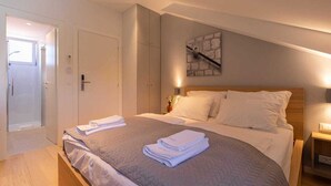 Ein Schlafzimmer mit einem Bett, einem Nachttisch, einem Wandbild und einer Tür zu einem Badezimmer.
