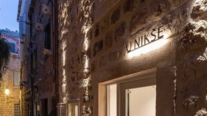 Un edificio de piedra con un letrero que dice "UNIKSE" y una puerta con un panel de vidrio.