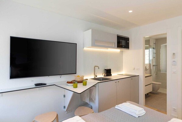 A modern kitchen with a flat-screen TV, a coffee machine, and a sink.