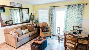 A living room with a sofa, armchair, coffee table, and a dining area with chairs and a table. - Gulf Shores Plantation 3305 (Gulf Shores)