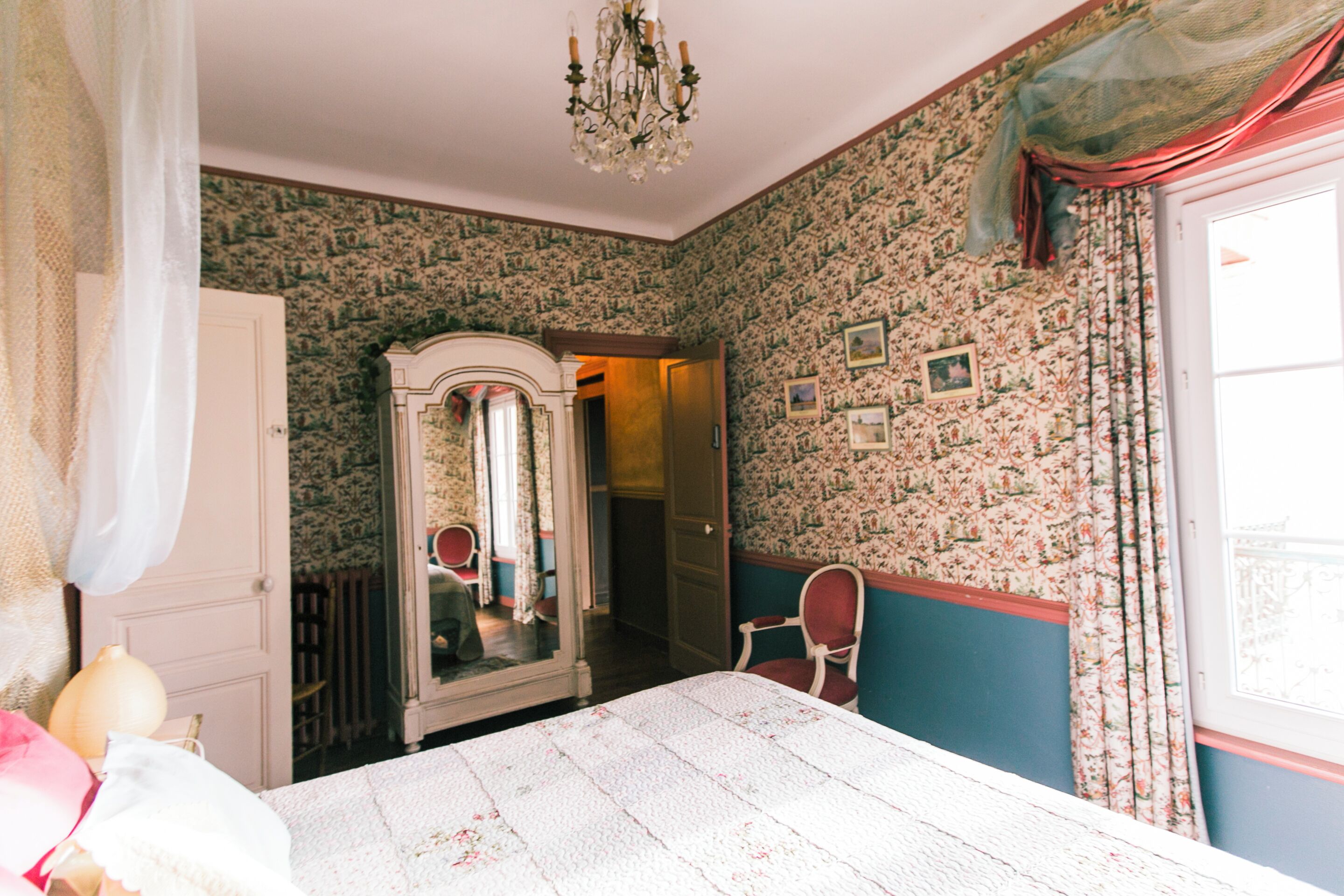 A room with a bed, a mirror, a chair, and a dresser.
