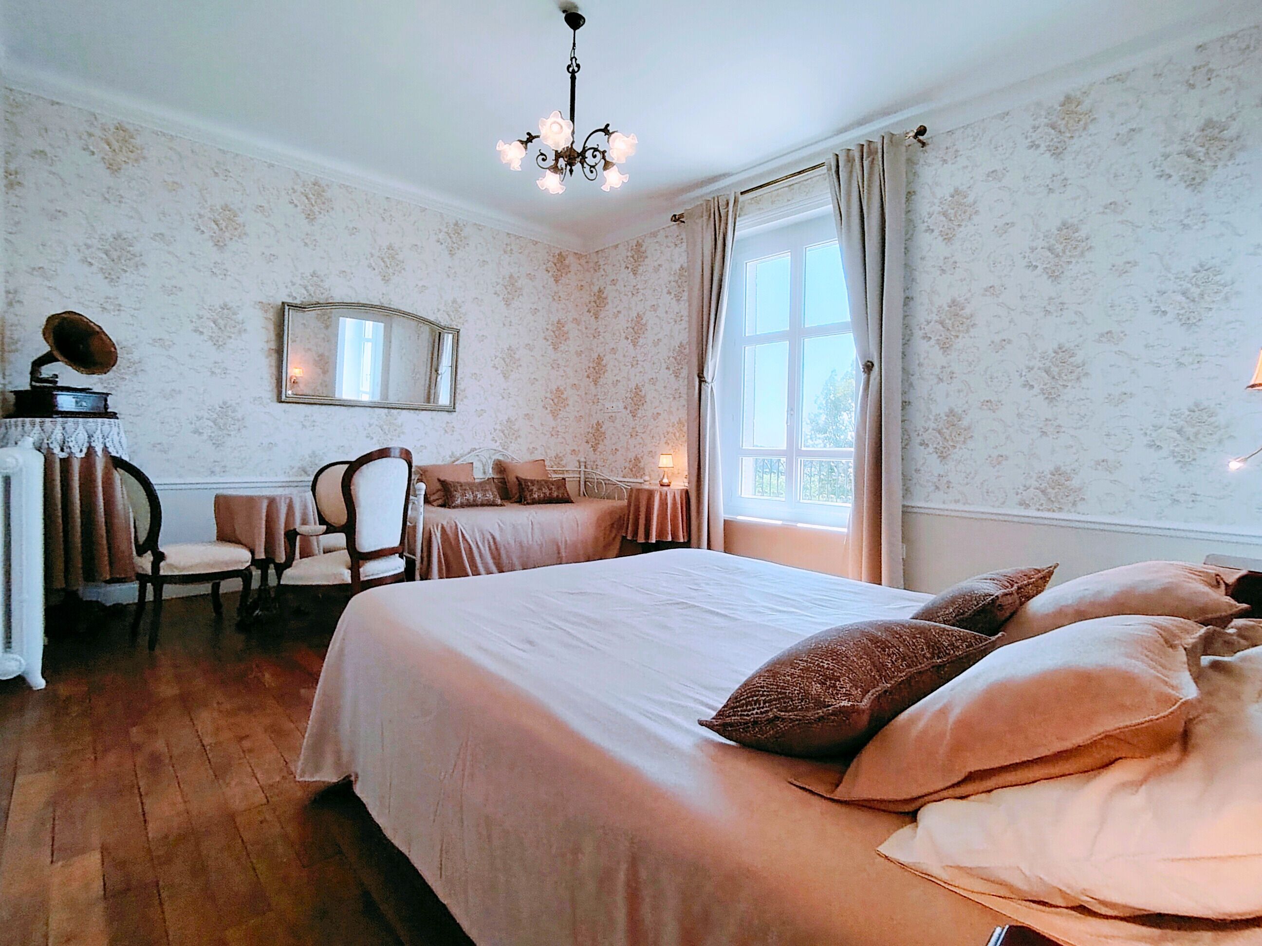 Ein Schlafzimmer mit einem großen Bett, einem Schreibtisch mit Stuhl, einem Spiegel und einem Fenster mit Vorhängen.