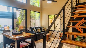 Uma sala de estar moderna com escada, janelas amplas e espaço para refeições.