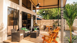 Un patio al aire libre techado con mobiliario de mimbre, una mesa de madera y sillas.
