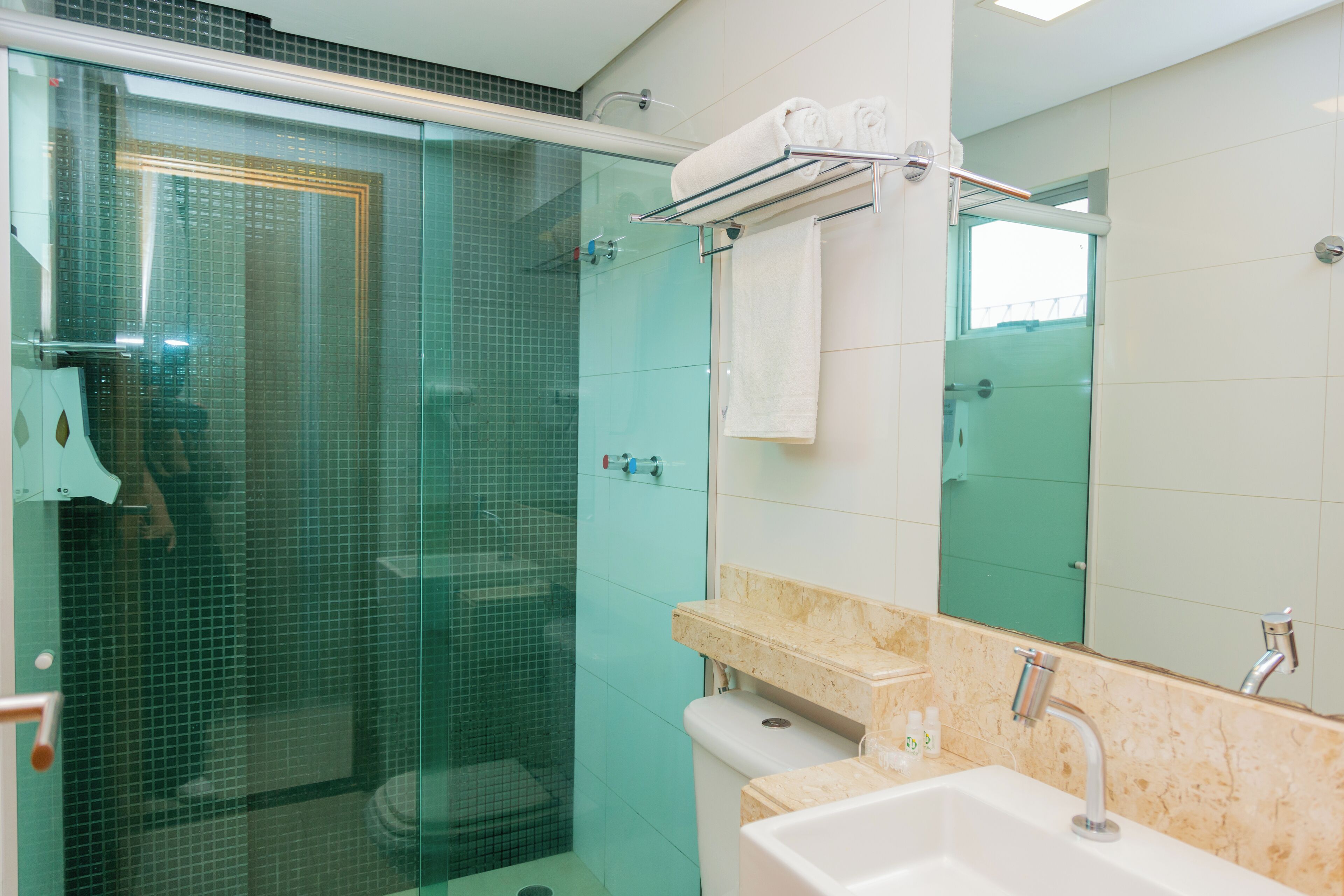 A modern bathroom with a glass-enclosed shower, a sink with a marble countertop, and a towel rack.