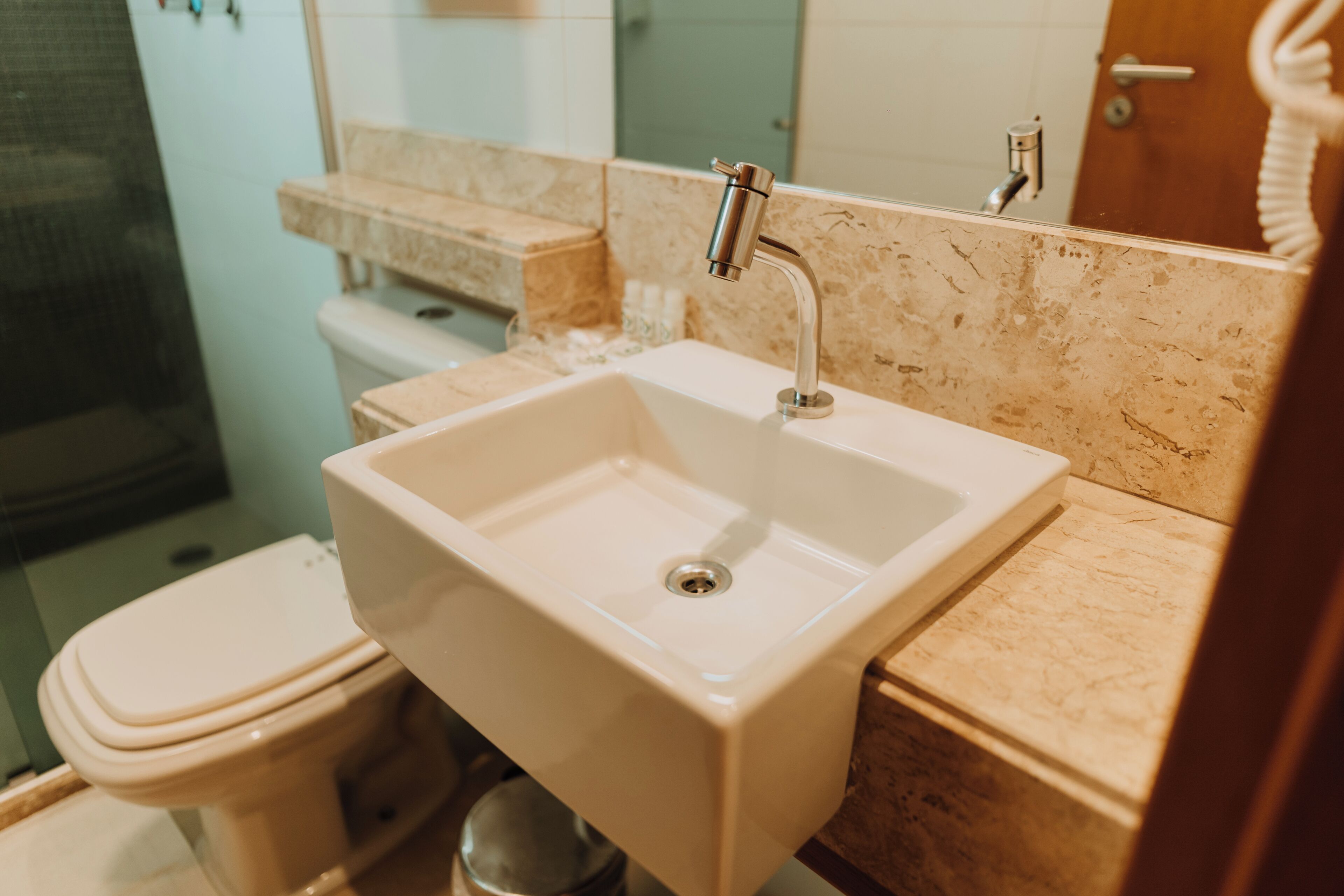 Une salle de bain avec un lavabo blanc, des toilettes et un miroir.