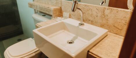 A bathroom with a white sink, a toilet, and a mirror.