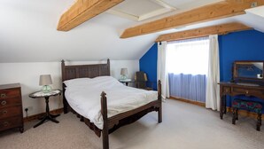 Camera da letto con un letto in legno, una cassettiera, un comodino e una scrivania con uno specchio.