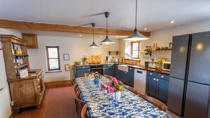 Una cucina con mobili in legno, un frigorifero e un tavolo da pranzo con tovaglia blu e fiori.