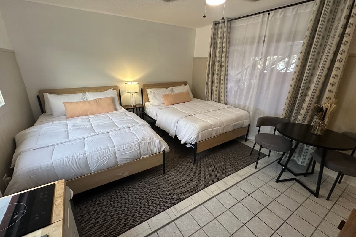 A hotel room with two beds, a desk, and a chair.