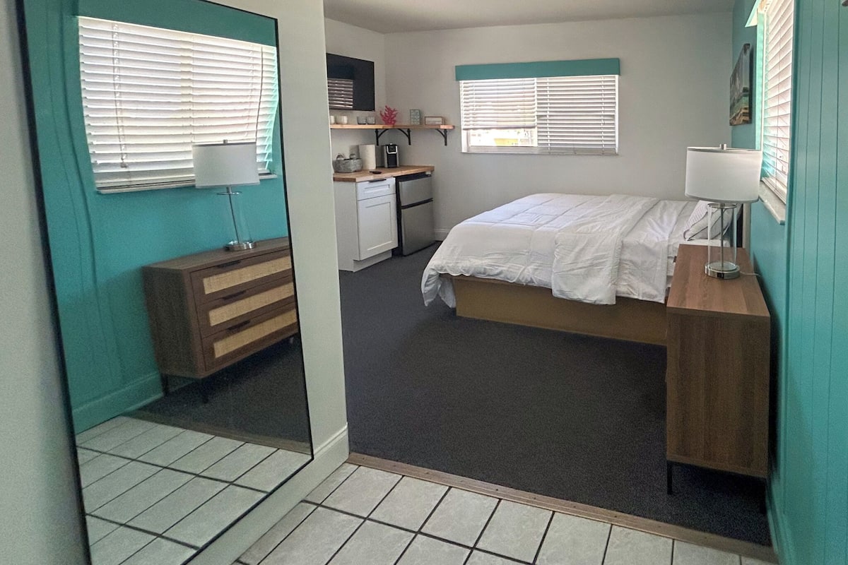 A compact bedroom with a bed, bedside table, and a mirror.