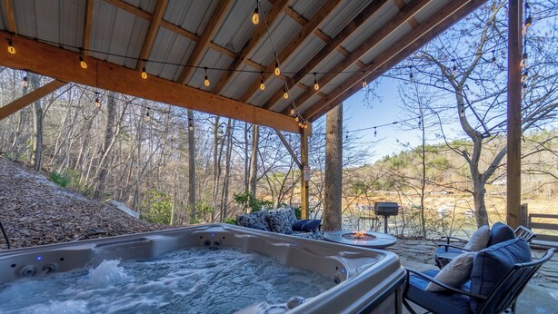 Un bain à remous avec une terrasse en bois, des sièges extérieurs et une vue sur une zone boisée.