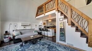 Un vaste espace de vie comprenant un salon avec une chambre en mezzanine, un coin repas et une cuisine.