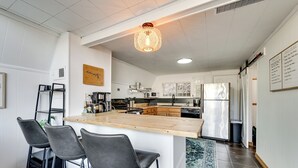 Une cuisine moderne dotée d’un îlot central, de tabourets de bar et d’un luminaire suspendu.