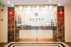 Een hotel receptiebalie met een marmeren aanrecht, een receptiegedeelte en een klok aan de muur.