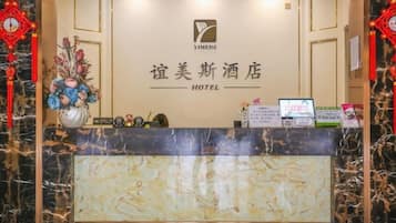 A hotel reception desk with a marble counter, a logo, and a sign in a foreign language.