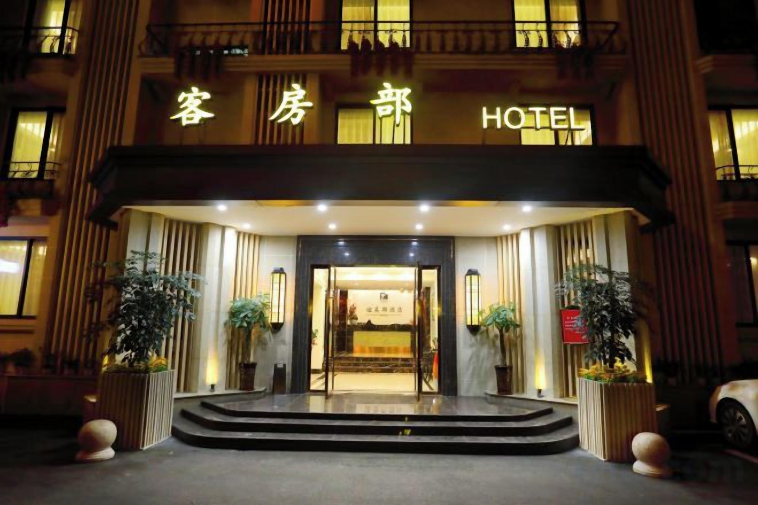 A hotel entrance with a sign, steps, and potted plants.