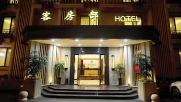 A hotel entrance with a sign, steps, and potted plants.
