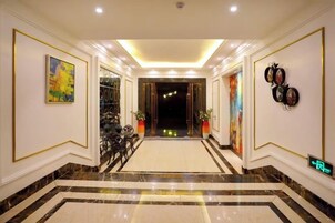 Un vestíbulo de hotel con piso de mármol, obras de arte enmarcadas y una recepción.
