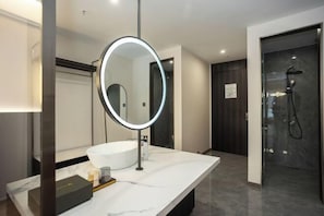 A modern bathroom with a large oval mirror, a white sink, and a glass-enclosed shower. - Yimesi Hotel (Dayi Food Street Store) (Dayi)
