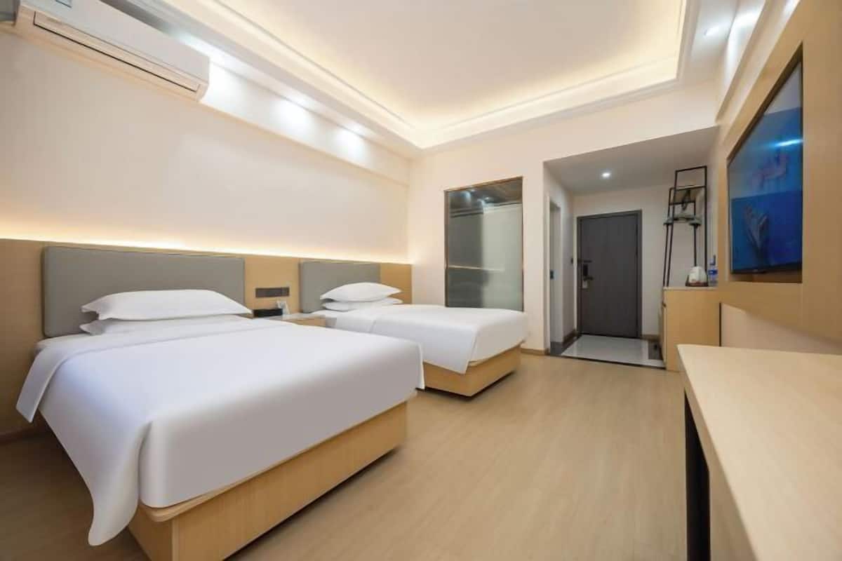 A hotel room with two beds, a desk, a mirror, and a door leading to a bathroom.