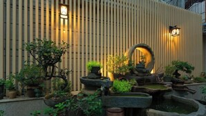 Un jardín zen con diversos maceteros y un elemento decorativo de piedra con agua.