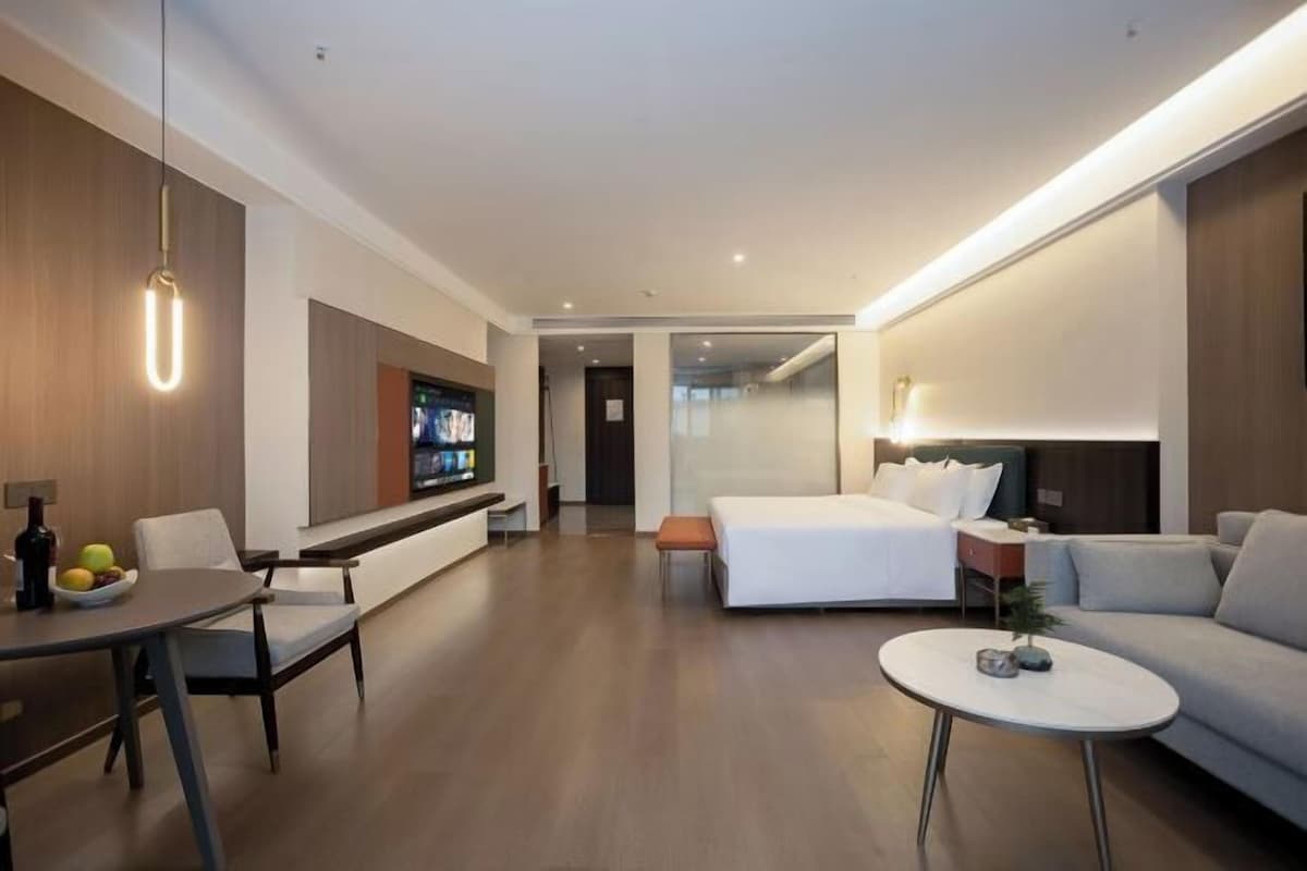 Una habitación de hotel moderna con comedor, cama y zona de estar.