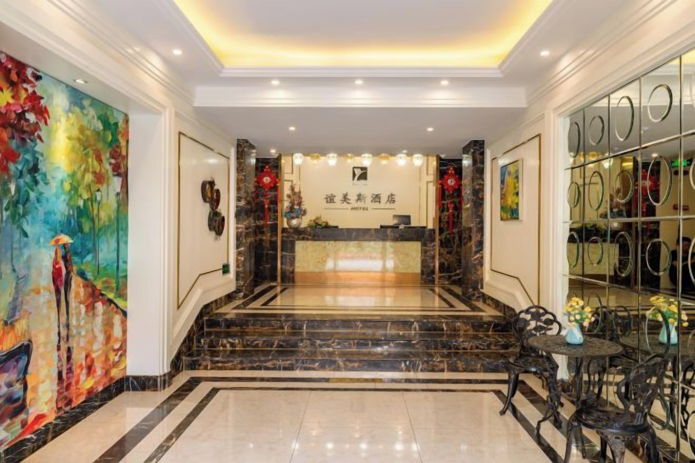 Zona de recepció d'un hotel amb un sòl de marbre, una taula de recepció i un quadre gran a la paret.