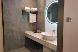 A modern bathroom with a large mirror, a round mirror, a white sink, and towels on a wall-mounted rack. - Yimesi Hotel (Dayi Food Street Store) (Dayi)