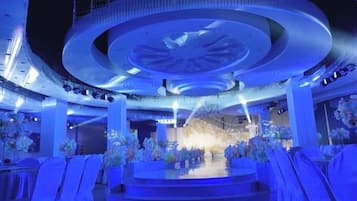 A venue with a circular stage, seating arrangements, and a chandelier.